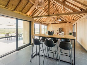 Cozinha moderna com interior em madeira, uma mesa de jantar grande e banquetas de bar.