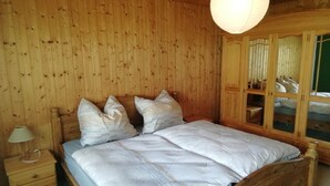 A wooden-paneled bedroom with a bed, nightstands, and a hanging light fixture. - Charmante Harzer Doppelhaushalfte (Osterode am Harz)