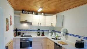 A compact kitchen with a dishwasher, oven, and a coffee maker. - Charmante Harzer Doppelhaushalfte (Osterode am Harz)