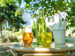 A glass table with a bottle and glasses on it, outdoors with greenery in the background. - Elegant Holiday Home in Fabrica di Roma near Theatre (Rome)