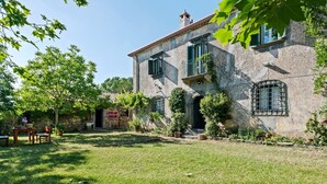 A stone building with a garden, a wooden table, and chairs. - Belvilla by OYO Casa Otaiti (Maniace)