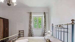 A bedroom with a bed, a window with curtains, a chandelier, and a wardrobe. - Belvilla by OYO Casa Otaiti (Maniace)