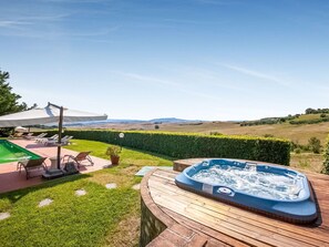 Una vasca idromassaggio su un pontile in legno con vista sulle dolci colline.