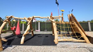 A playground with a wooden climbing structure, a slide, and a swing set. - Cottage in Cisowo Near Baltic Coast Beach (Darlowo)