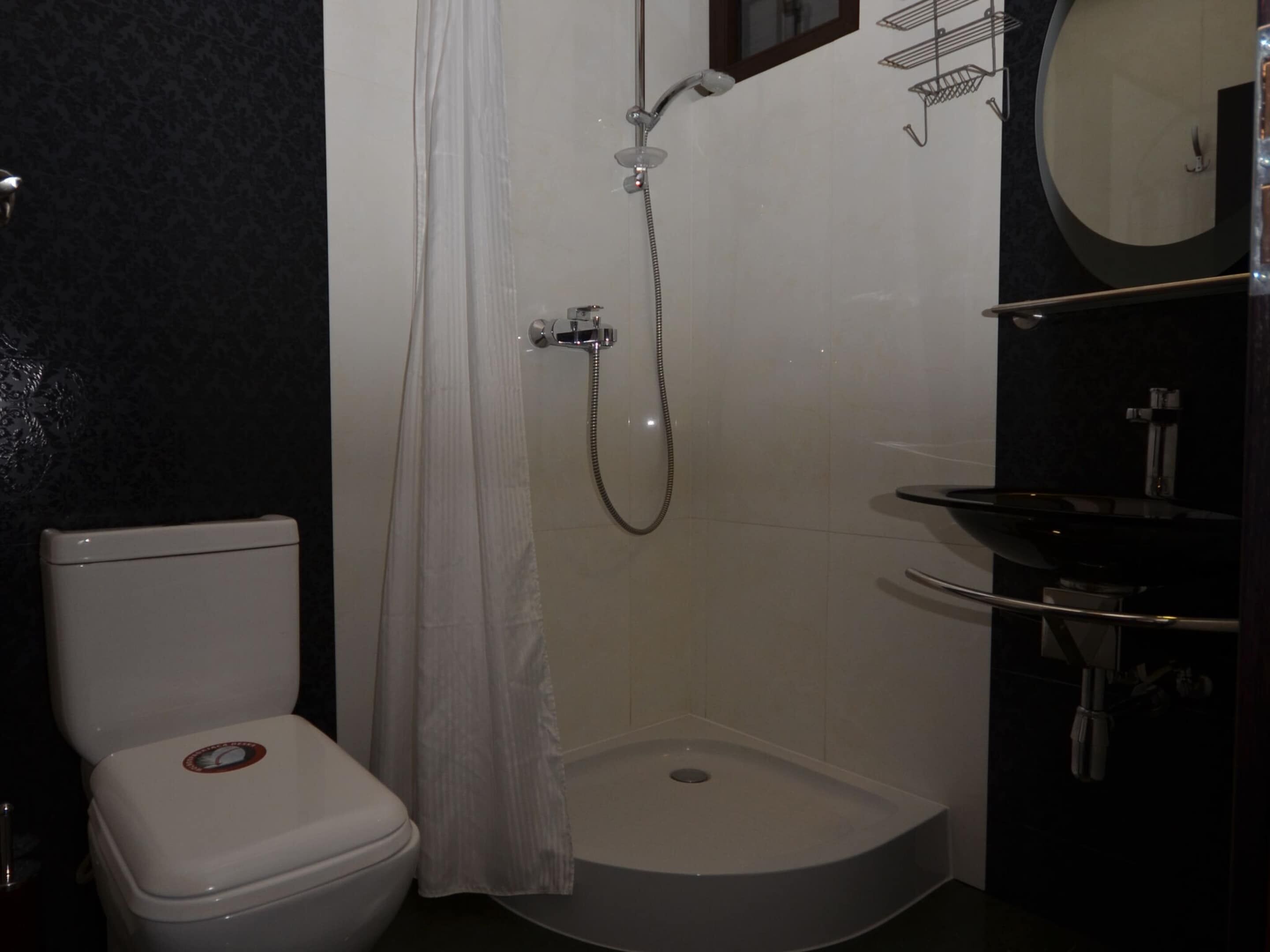 A bathroom with a toilet, a shower, and a sink.