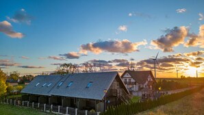 A wooden house with a sloped roof and skylights, surrounded by a fence and trees. - Cottage in Cisowo Near Baltic Coast Beach (Darlowo)