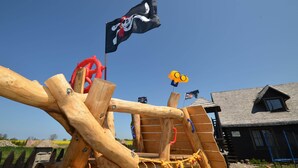 A wooden play structure with a pirate flag, a yellow Minion flag, and a small flag. - Cottage in Cisowo Near Baltic Coast Beach (Darlowo)