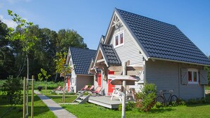 Duas pequenas casas com telhados inclinados, um deck de madeira e uma bicicleta.