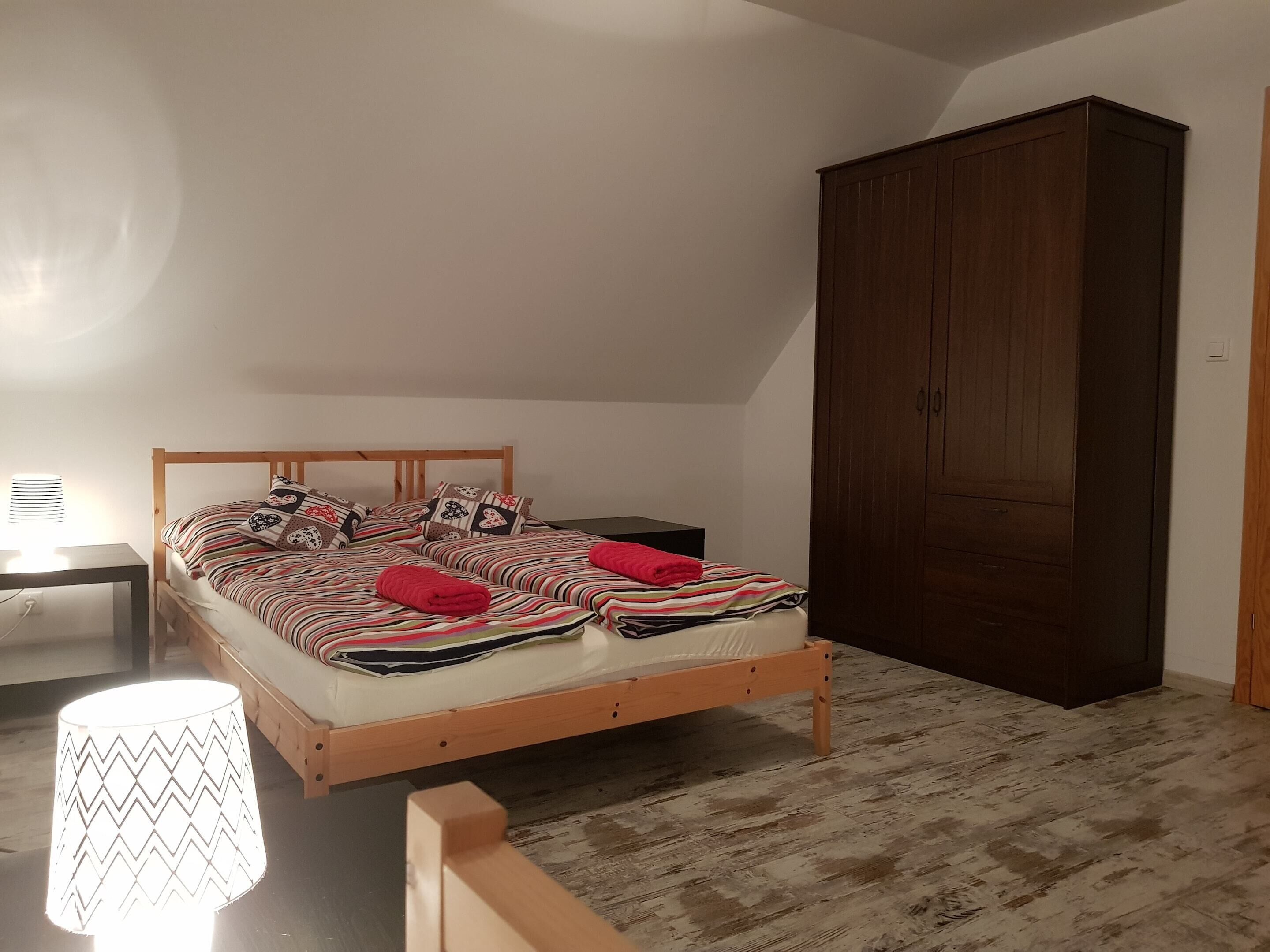 Ein Schlafzimmer mit einem hölzernen Bett, einem Nachttisch, einer Lampe und einem Kleiderschrank.