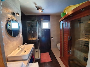Un baño moderno con tocador, ducha y retrete.
