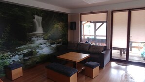 Un salon moderne avec un plancher en bois, un canapé, une table basse et un grand tableau représentant une cascade.