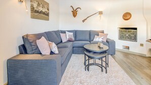 A modern living room with a grey sectional sofa, a round coffee table, and a fireplace.
