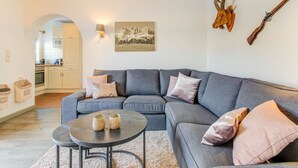 A modern living room with a grey sectional sofa, a round coffee table, and a mounted deer head.