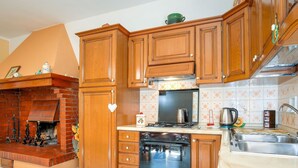 Eine Küche mit Holzschränken, einem Kamin aus Ziegelsteinen und einer gefliesten Spritzschutzwand.