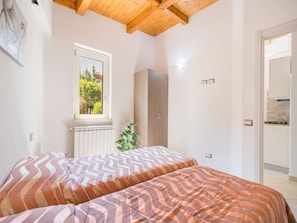 Camera da letto con un letto, una finestra, un termosifone, un armadio e angolo cottura.