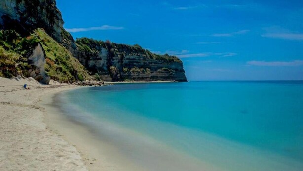 A beach with clear turquoise water, sandy shore, and a rocky cliff. - Apartment in Gasponi With Mountain Views (Drapia)