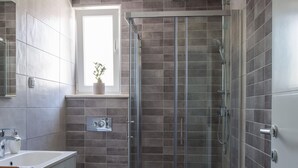 Ein modernes Badezimmer mit einer gläsernen Duschkabine, einer Toilette und einem Waschbecken.