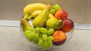 Eine Obstschale mit Bananen, Birnen, Trauben und einem Apfel.