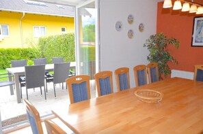 A dining area with a wooden table and chairs, a glass door leading outside, and a potted plant. - Chalet mit Sauna und Sommergastekarte Zell am See (Zell am See)