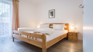 A wooden bed with two pillows and a nightstand with a lamp. - Chalet mit Sauna und Sommergastekarte Zell am See (Zell am See)