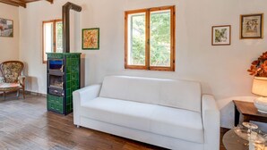 A room with a white sofa, wooden ceiling beams, a green cabinet, and framed pictures on the walls. - Holiday Home in Tuscany With Private Garden (Pieve Santo Stefano)