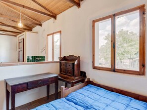A bedroom with a wooden bed, a wooden dresser, a desk, and a window with a view of trees. - Holiday Home in Tuscany With Private Garden (Pieve Santo Stefano)