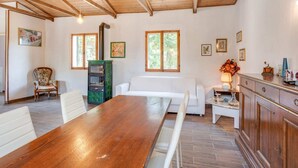 A spacious room with a wooden dining table, white sofas, a built-in oven, and a kitchen area with wooden cabinets. - Holiday Home in Tuscany With Private Garden (Pieve Santo Stefano)