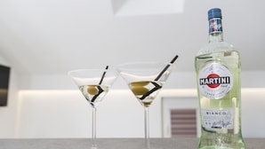 Two martini glasses with olives and straws on a countertop next to a bottle of Martini Bianco. - Plush Apartment in Imotski near Blue & Red Lakes (Imotski)