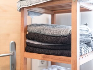 A wooden shelf with folded towels in various shades of gray and black. - Scenic Apartment in Ulrichsberg near Museum & Jazz Club (Ulrichsberg)