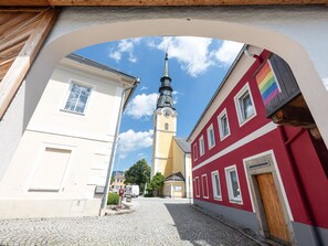 A cobblestone street with buildings, a church tower, and a rainbow flag. - Scenic Apartment in Ulrichsberg near Museum & Jazz Club (Ulrichsberg)
