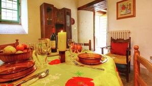 A dining room with a table set for four, featuring a floral tablecloth, a candle, and a bottle of wine. - Belvilla by OYO Casina del Forno (Rufina)