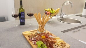 Ein Wäscherbrett mit Käse, Wurstwaren, Nüssen und Trauben auf einer Holzplanke, dazu Weingläser und eine Weinflasche.