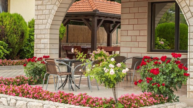 Eine Außenpatio mit einem Backsteinbogen, einer Pergola und einem Tisch mit Stühlen.