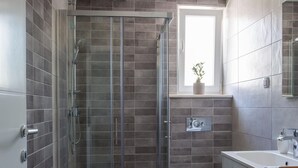 Ein modernes Badezimmer mit einer Duschkabine, einer Toilette und einem Waschbecken mit Spiegel.