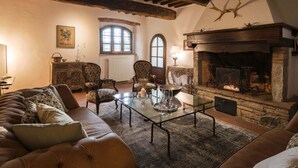Un salon chaleureux avec une cheminée, un canapé en cuir et des poutres en bois au plafond.