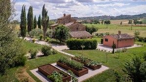 Une maison de campagne avec un jardin, entourée de champs et d’arbres.