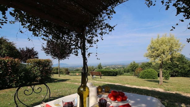 An outdoor dining setup with a table, food, and wine, surrounded by greenery and a scenic view. - Farmhouse in Casperia With Pool & Scenic Views (Casperia)