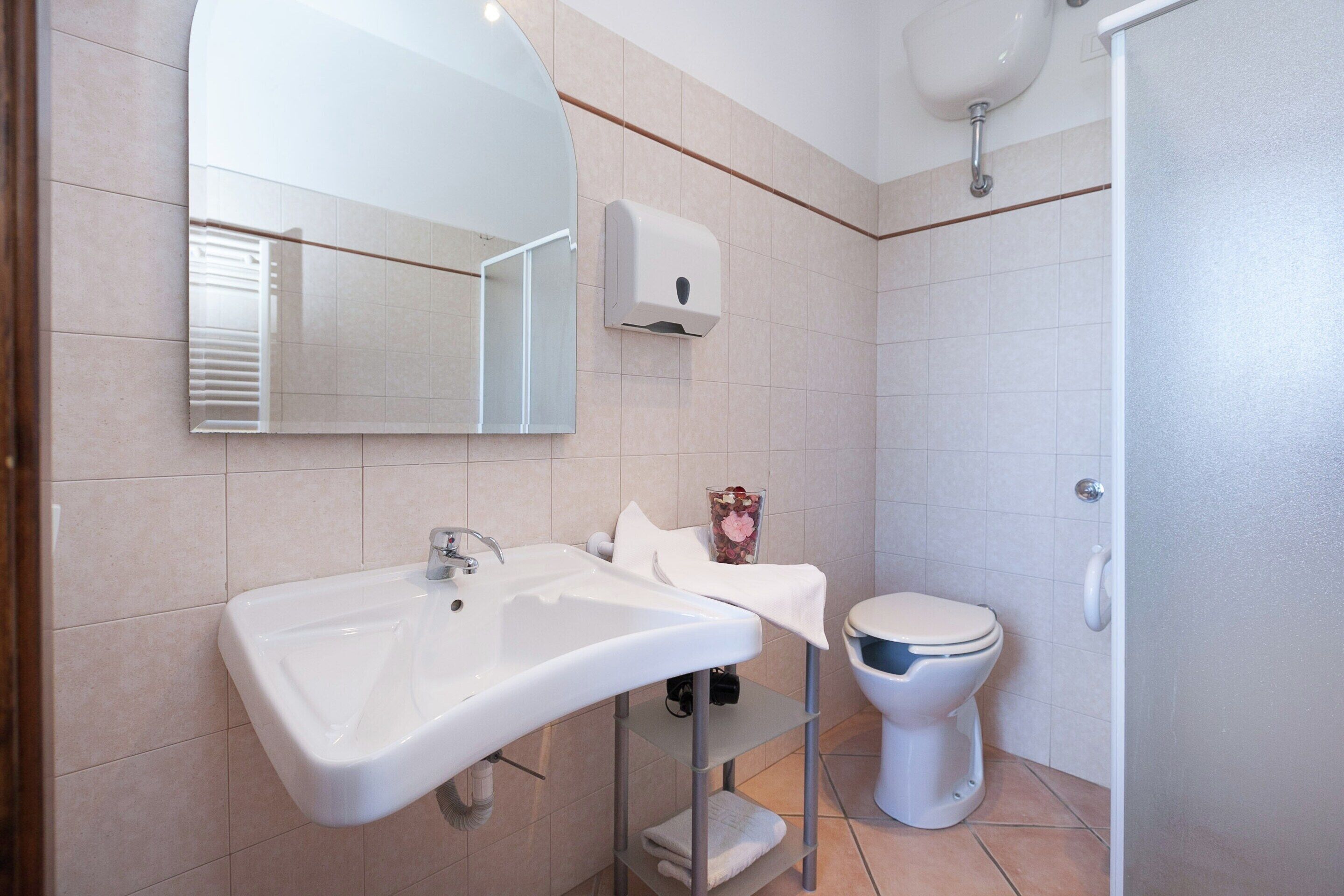 A modern bathroom with a large sink, a toilet, and a mirror.