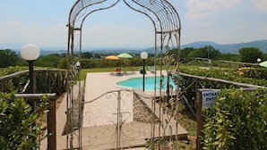 A pool area with a wrought iron archway, a sign indicating an entrance, and a view of the landscape. - Farmhouse in Casperia With Pool & Scenic Views (Casperia)