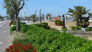 A coastal promenade with a clear sky, a Ferris wheel, and a beach area with palm trees and flower beds. - Spacious Villa With Garden and Terrace in the Green Hinterland of Rimini (Montescudo)