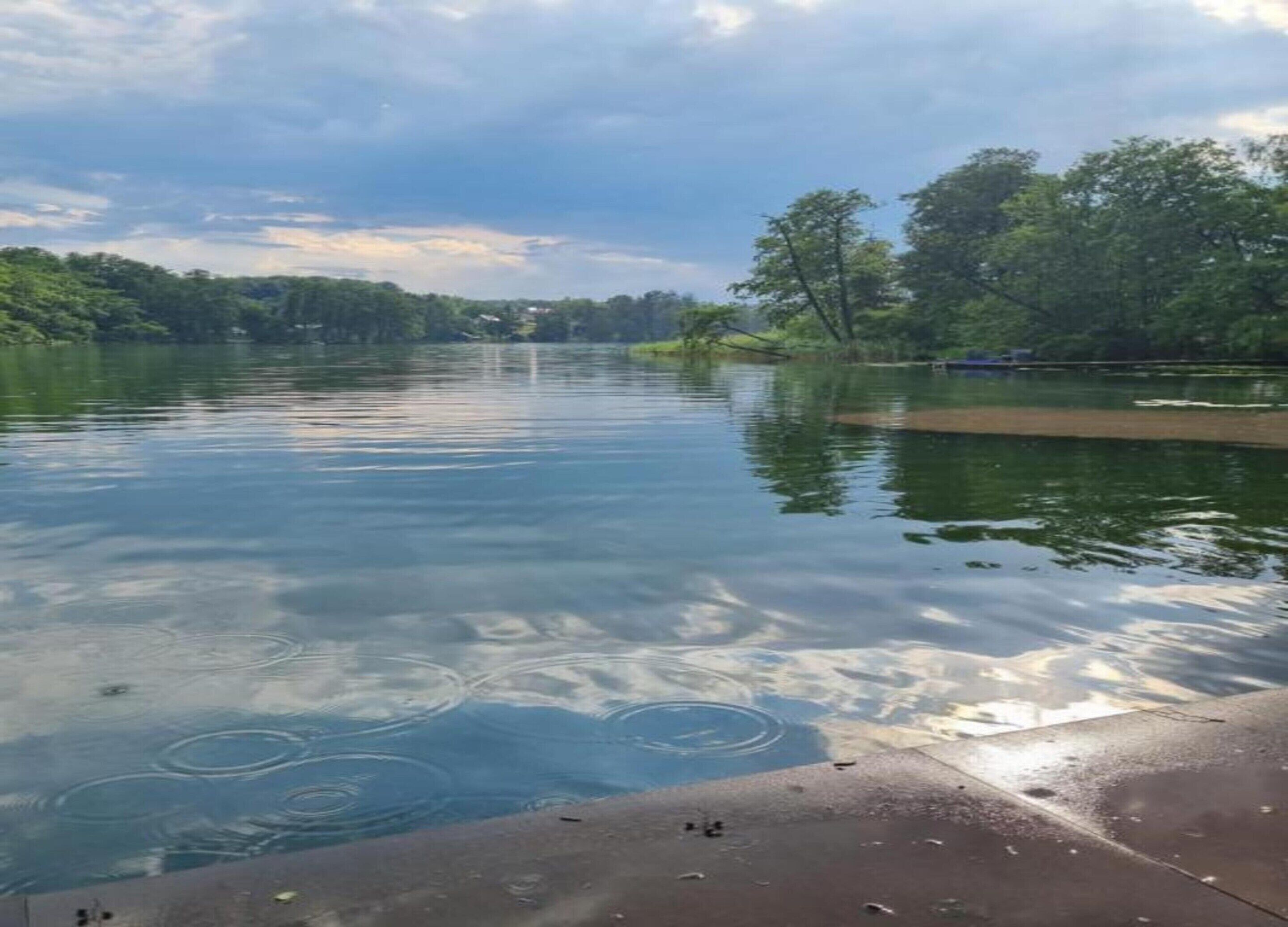 A calm river with clear water reflecting the sky and surrounding greenery.