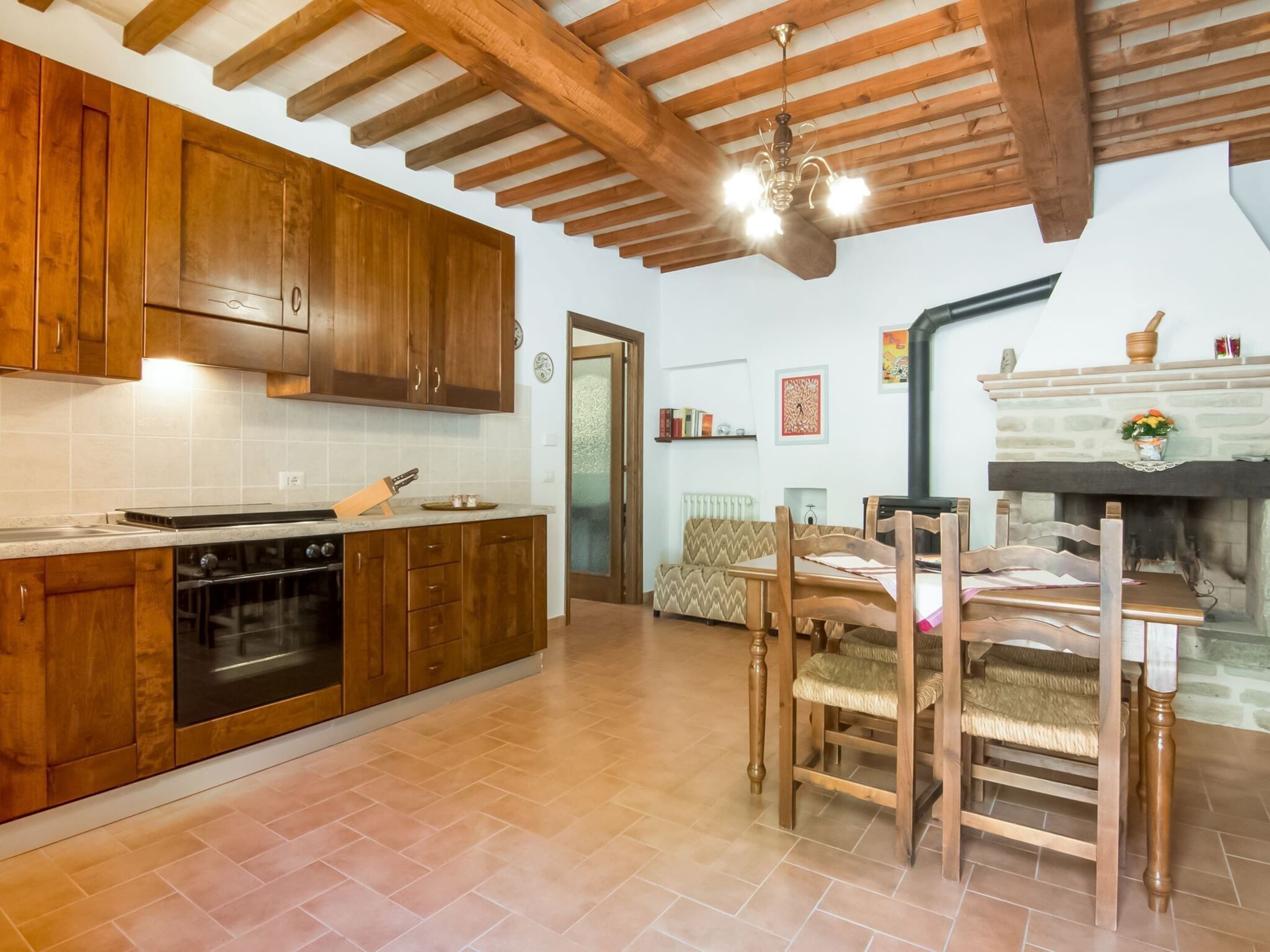 A kitchen with wooden cabinets, a stove, and a dining area with wooden chairs and a table.