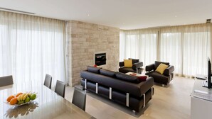 Een moderne woonkamer met een zithoek, een eettafel met stoelen en een televisie.