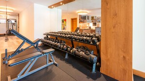 Uma academia com equipamentos de ginástica, incluindo um banco e halteres.