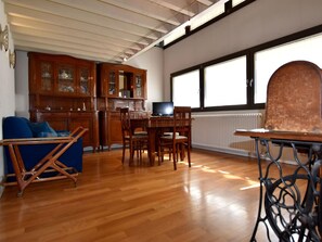 A spacious living area with a wooden dining table, blue sofa, and a television. - Cozy Apartment in Lovere near Lake (Lovere)