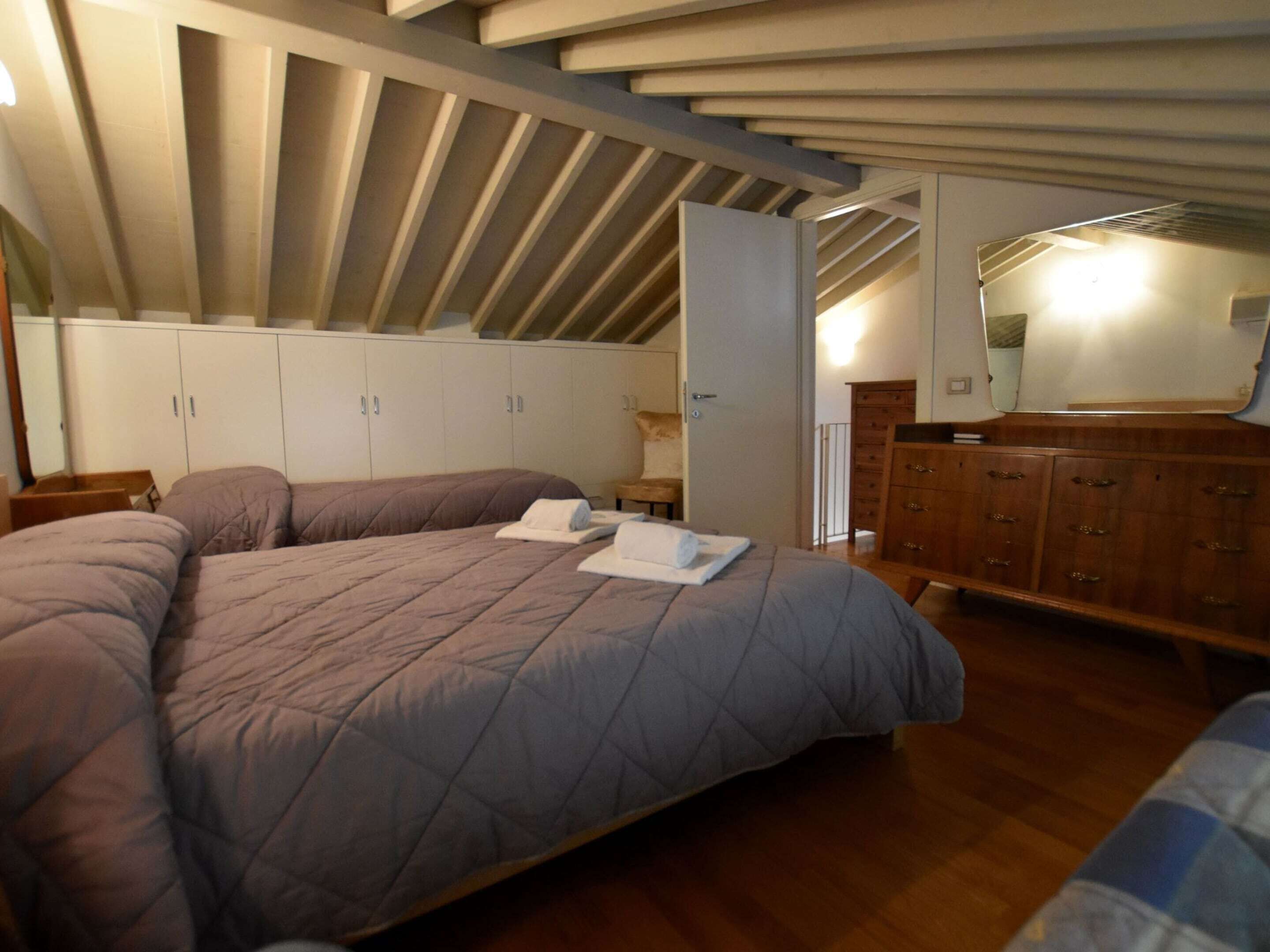 A bedroom with a large bed, a wooden dresser, and a wardrobe.