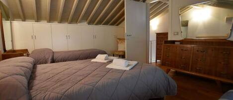 A bedroom with a large bed, a wooden dresser, and a wardrobe.