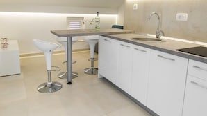 A modern kitchen with white cabinets, a stainless steel sink, and bar stools. - Pretty Apartment in Imotski near River (Imotski)
