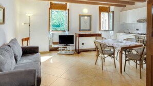 A cozy living room with a sofa, a TV, and a dining area with chairs and a table.