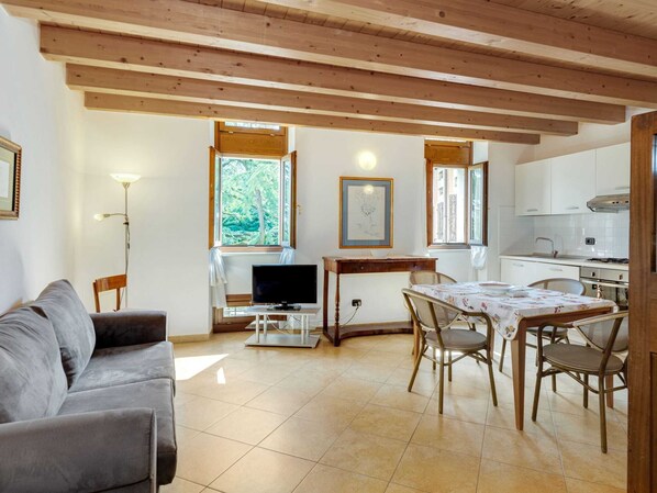 A cozy living room with a sofa, a TV, and a dining area with chairs and a table.